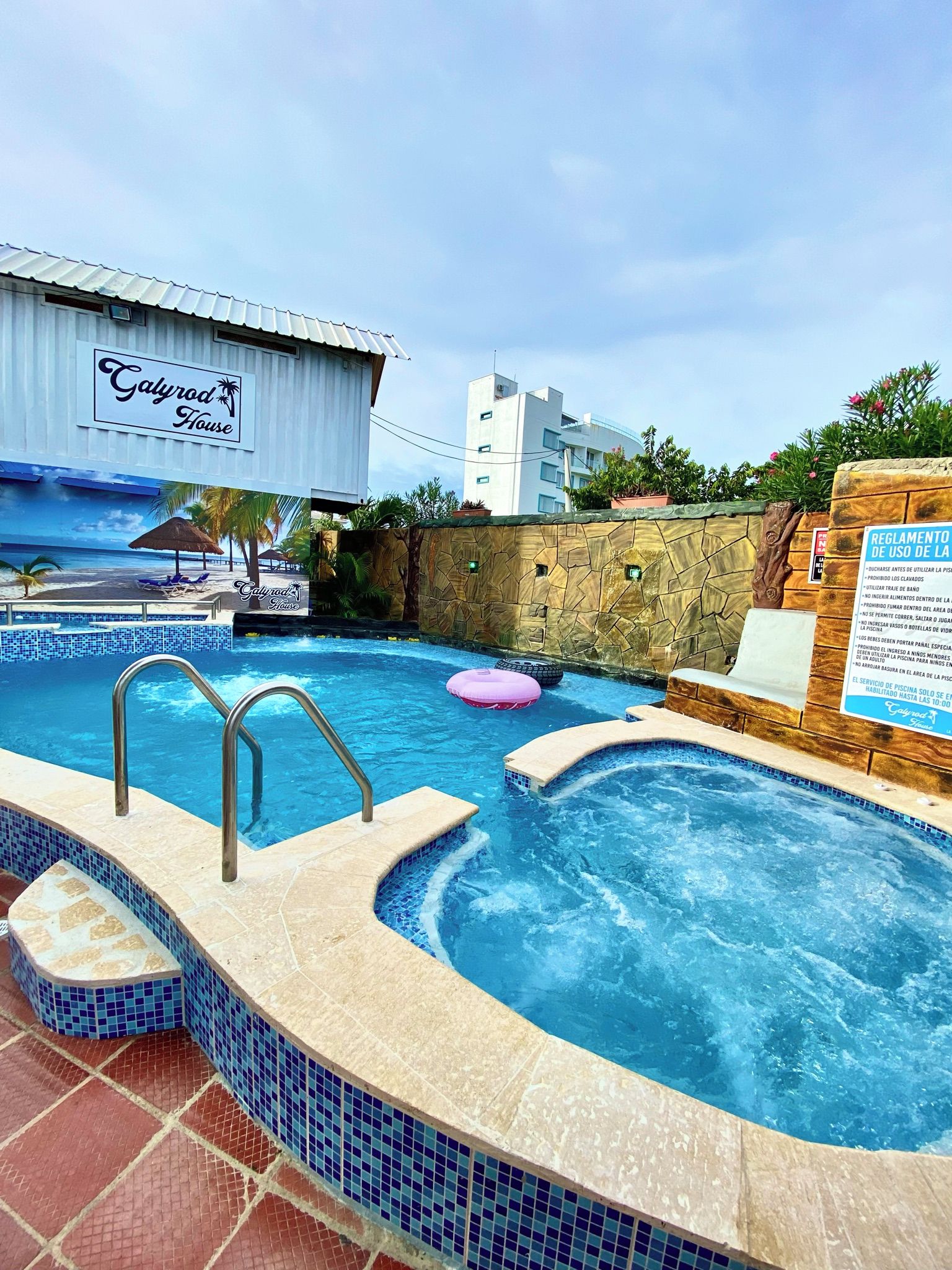 Ein Hotelpoolbereich mit Whirlpool, Liegestühlen und einem Schild, das die Poolnutzungsregeln anzeigt.