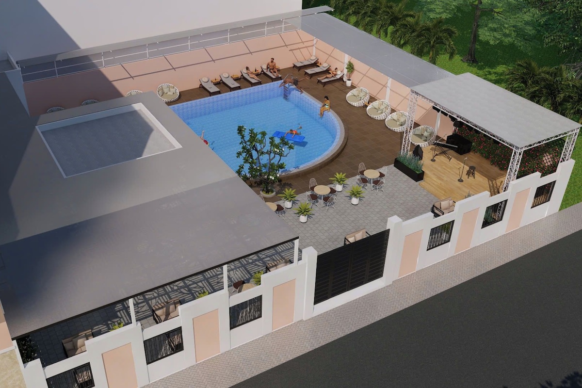 Un área de piscina en la azotea con sillones de descanso y un pequeño escenario.