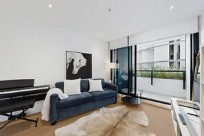 Ein modernes Wohnzimmer mit einem Klavier, einer Couch und einem großen Fenster.
