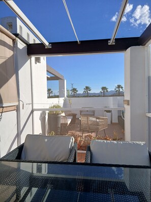 A balcony with a glass table, wicker chairs, and potted plants. - Cielo Dorado – Luxury Ibiza-Style Apartment with Sunny Rooftop (Alhama de Murcia)
