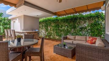 Eine Terrasse im Freien mit Esstisch, Stühlen, einer Couch und Deckenventilator.