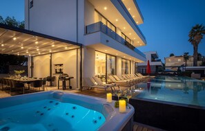 Uma área de piscina moderna ao ar livre, com hidromassagem, espreguiçadeiras e espaço para refeições.