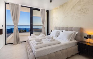 A hotel room with a bed, a nightstand, a lamp, and a view of the sea through large windows. - Cozy home in Kastel Stari with private swimming pool, can be inside or outside (Kastel Stari)