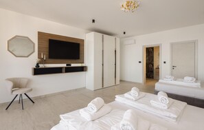 A modern hotel room with a large flat-screen TV, a wardrobe, a seating area with a chair, and a bed with neatly folded towels. - Cozy home in Kastel Stari with private swimming pool, can be inside or outside (Kastel Stari)