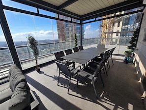 A modern conference room with a large table and chairs, large windows with a city view, and a potted plant. - JTower Royal Suites & Penthouse (Jerusalem)