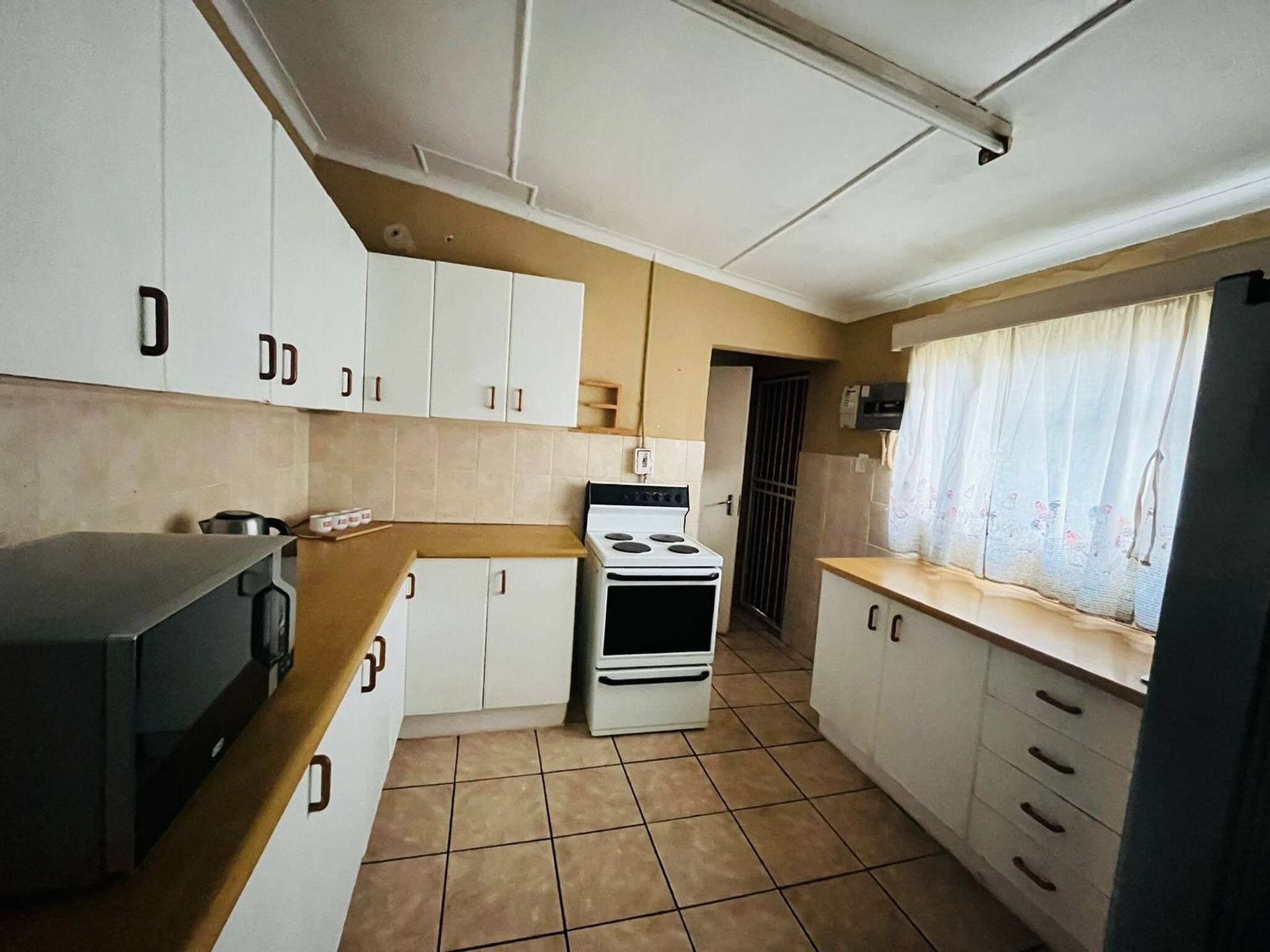 Une cuisine de taille réduite avec des meubles blancs, une cuisinière et un four à micro-ondes.