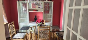 A dining area with a glass-top table, wicker chairs, and a white cabinet with glass doors containing glassware. - Entire house or single room open to all offers (Ottawa)