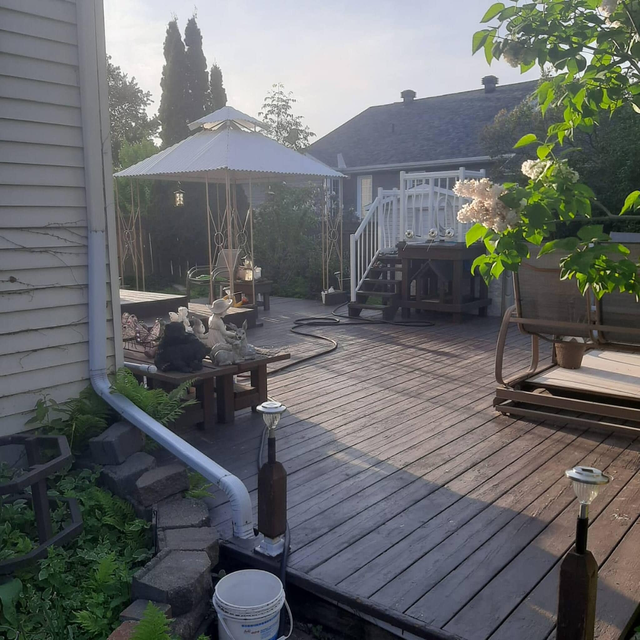 A wooden deck with outdoor furniture, a gazebo, and a white fence.