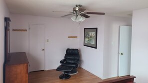 A room with a ceiling fan, a black leather chair, a wooden cabinet, and a framed picture on the wall. - Entire house or single room open to all offers (Ottawa)
