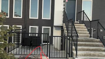 Un immeuble résidentiel à plusieurs étages, doté d’une façade sombre, de nombreuses fenêtres et d’un escalier avec une rampe noire.