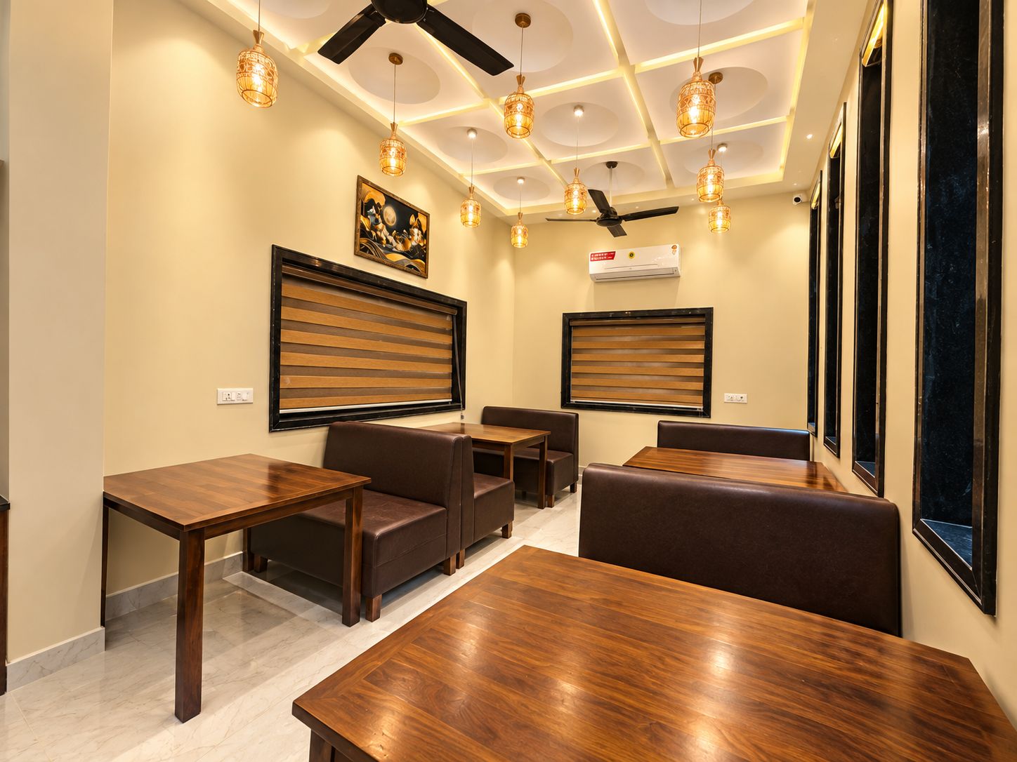 A hotel room with a ceiling fan, pendant lights, a large window, and a wooden table.