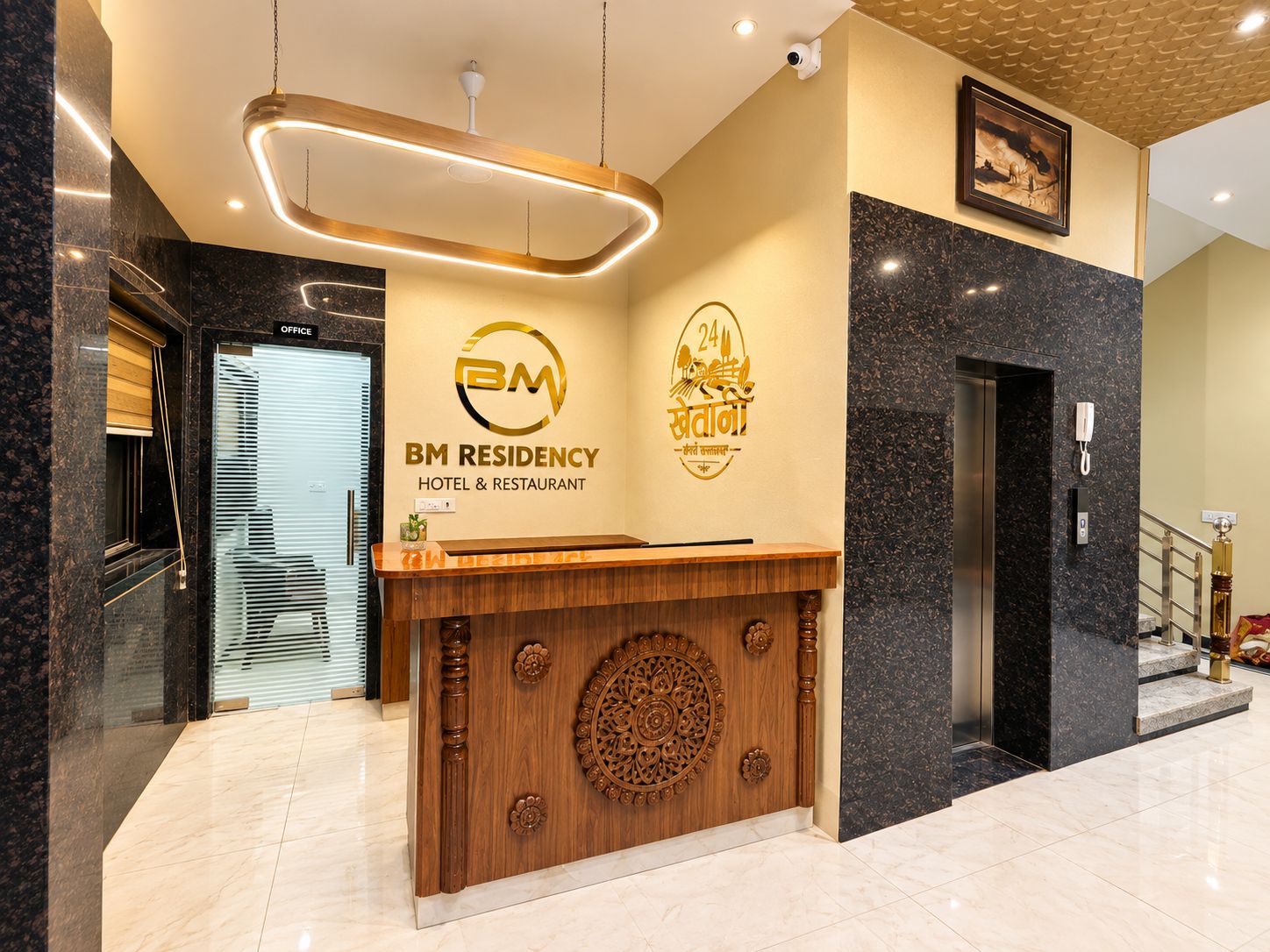 A hotel reception desk with a wooden counter and a modern light fixture above.