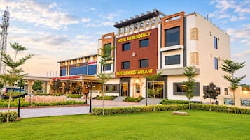 Un hotel con restaurante y gimnasio, rodeado de vegetación y un cielo despejado.