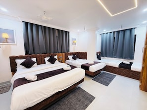Une chambre d’hôtel avec deux lits, une grande fenêtre avec des rideaux, une tête de lit et une lampe fixée au mur.