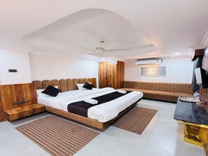 Une chambre moderne avec un grand lit, une tête de lit en bois, un banc et un téléviseur à écran plat.