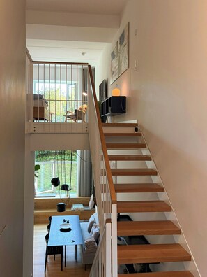 Un interior de varios niveles con una escalera, un comedor y vistas al exterior.