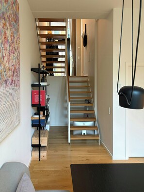A modern interior with a staircase, a bookshelf, and a hanging lamp. - Two-storey flat by Carlsberg's garden (København)