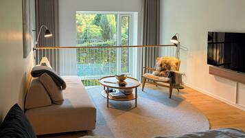A modern living room with a sofa, a round coffee table, a chair, and a television mounted on the wall.