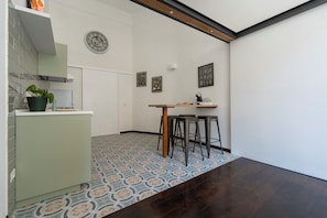 A compact kitchen with a patterned floor, a clock, and a small dining area with stools. - Living Filomarino (Naples)