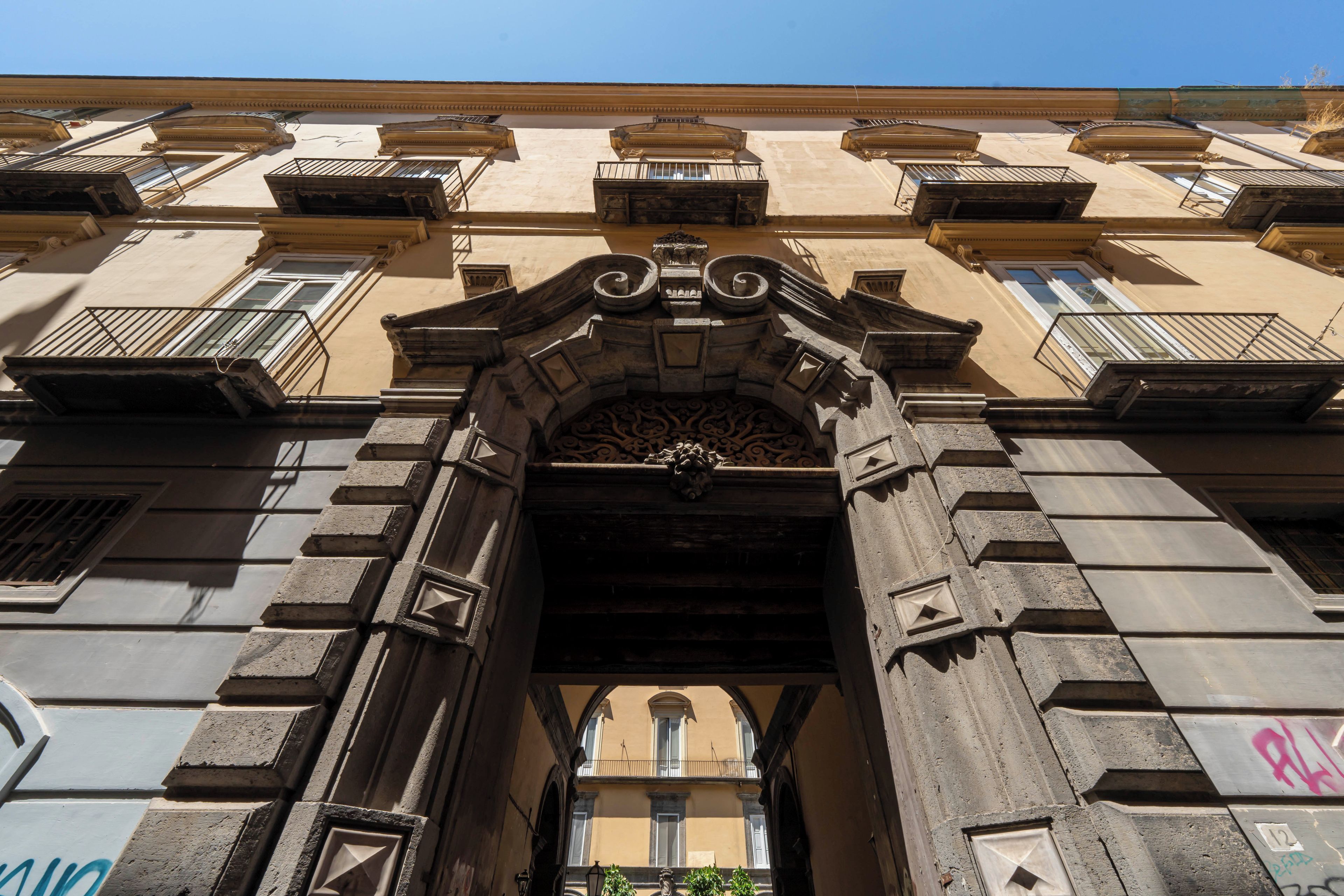 Una entrada arquitectónica ornamentada con un arco central, flanqueado por balcones y ventanas.