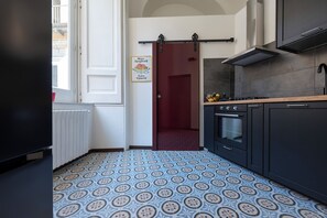 A kitchen with a patterned floor, a sliding door, and a stove. - Living Filomarino (Naples)