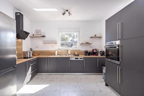 A modern kitchen with grey cabinets, a wooden countertop, and a built-in oven. - Villa Blue Lagoon (Krsan)