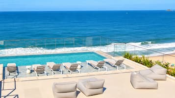 A poolside area with lounge chairs and a view of the ocean.