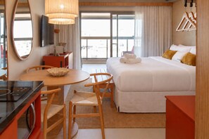 A hotel room with a bed, a desk, a chair, a round table, a television, and a window with curtains. - Charlie IPA Design Studios Ipanema (Rio de Janeiro)