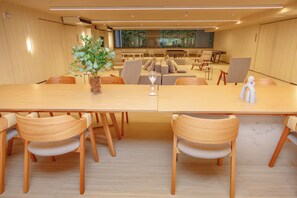 A modern meeting room with a long table, comfortable seating, and a large window. - Charlie IPA Design Studios Ipanema (Rio de Janeiro)