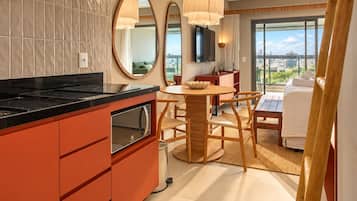 Une cuisine moderne avec un plan de travail noir, un four encastré et un coin repas comprenant une table ronde et des chaises.