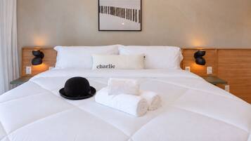 A hotel room with a large bed, two bedside tables, a wall-mounted picture, and a name pillow.