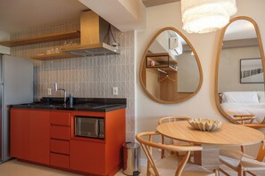 Una cocina moderna con armarios rojos, horno empotrado y campana extractora de acero inoxidable.
