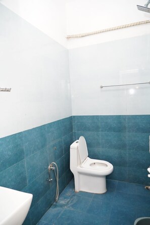 A bathroom with a toilet, a shower, and a sink. - REHO RESORT (Rameshwaram)