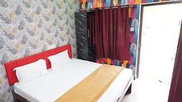 Una cama con cabecera roja, ropa de cama blanca y una manta marrón.