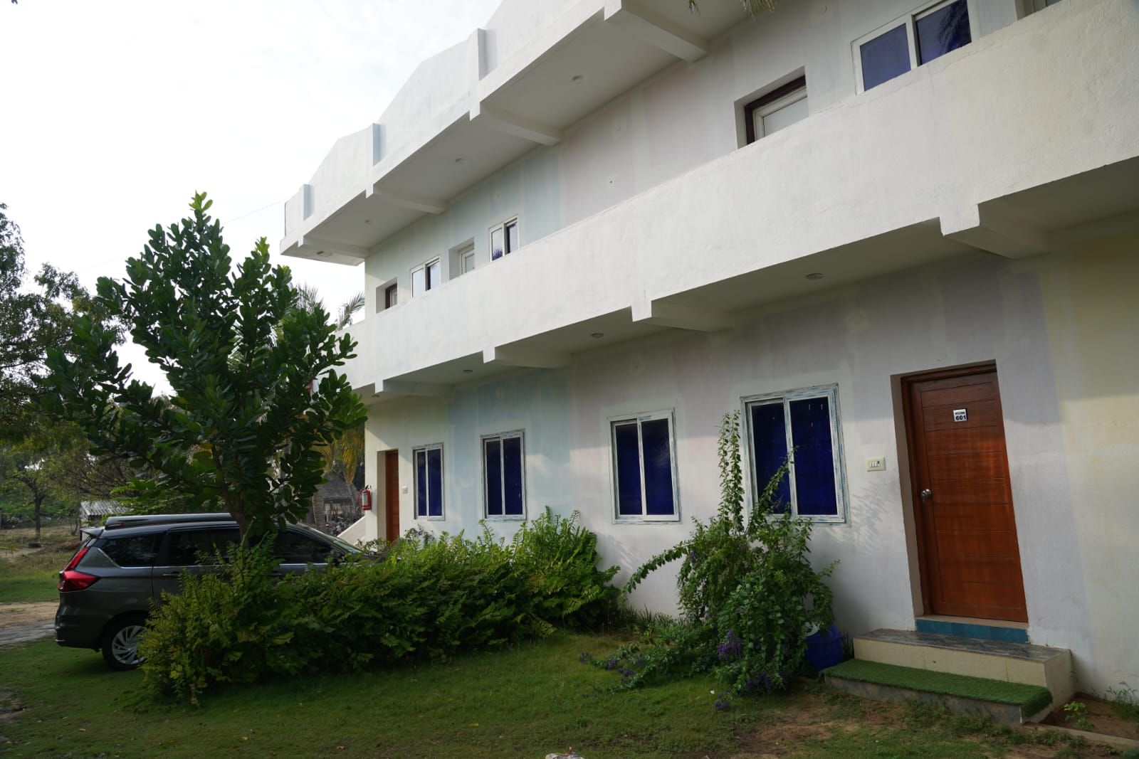 A two-story building with a flat roof, multiple windows, and a front door.