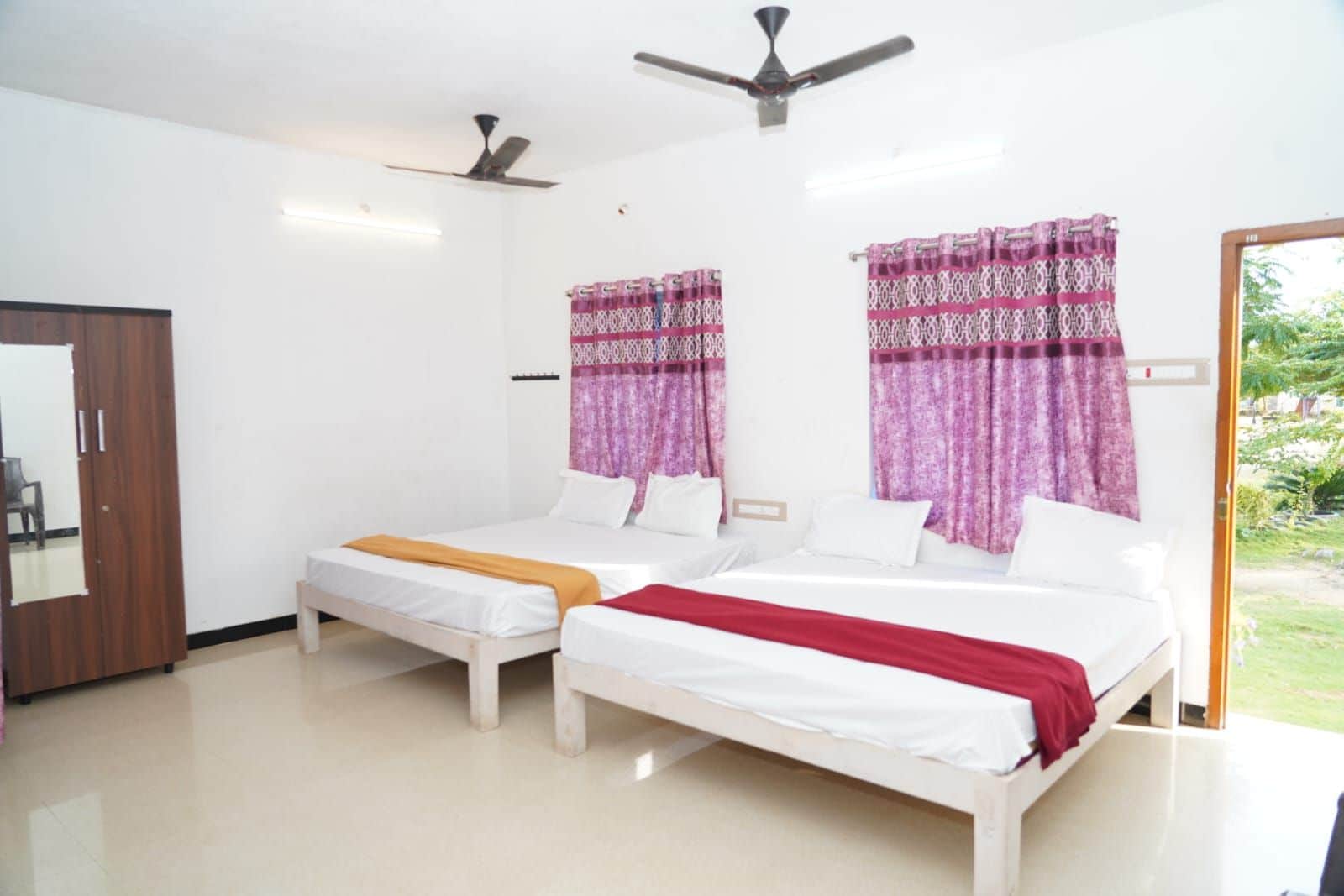 Habitación de hotel con dos camas, ventilador de techo y vistas al exterior.