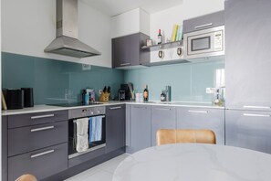 Eine moderne Küche mit Einbauofen, Mikrowelle und einem Essbereich mit Tisch und Stühlen.
