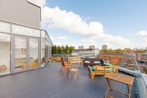 Eine Dachterrasse mit Außenbestuhlung, einem Wintergarten und Blick auf die Stadt.