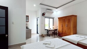 A room with two beds, a desk with a chair, a wardrobe, and a small kitchen area. - Fshome – Vung Tau Branch (HO CHI MINH)