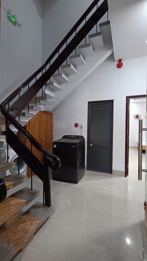 A staircase with a wooden handrail leading to a landing where a black appliance is located. - Fshome – Vung Tau Branch (HO CHI MINH)