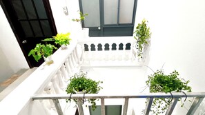A white balcony with potted plants and a white railing.
