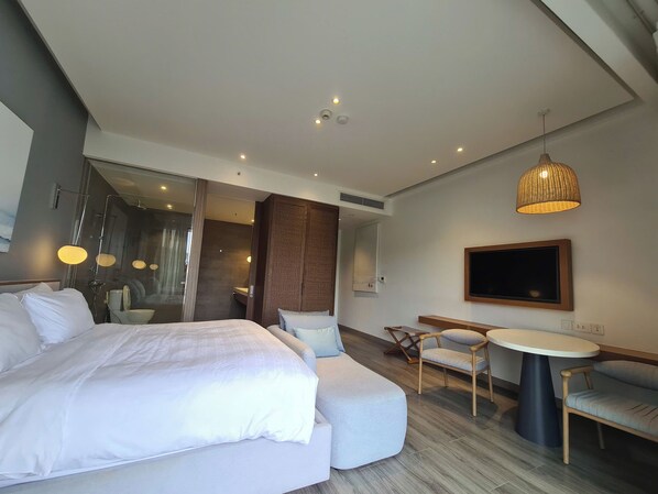 A modern hotel room with a large bed, a seating area with a table, and a television. - Lagoon Residences (Phu Quoc)