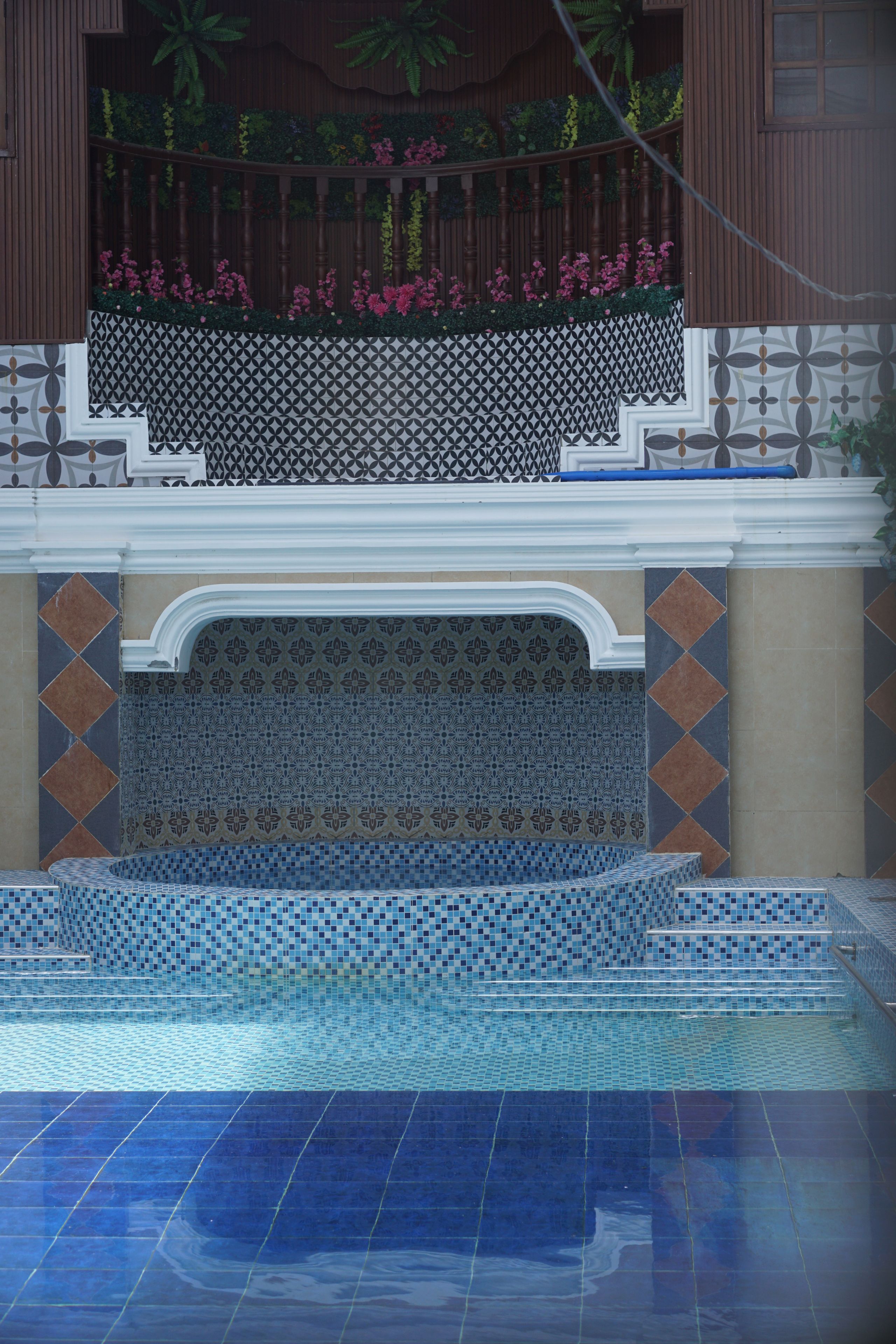 A swimming pool with a tiled edge and a decorative wall with a geometric pattern.
