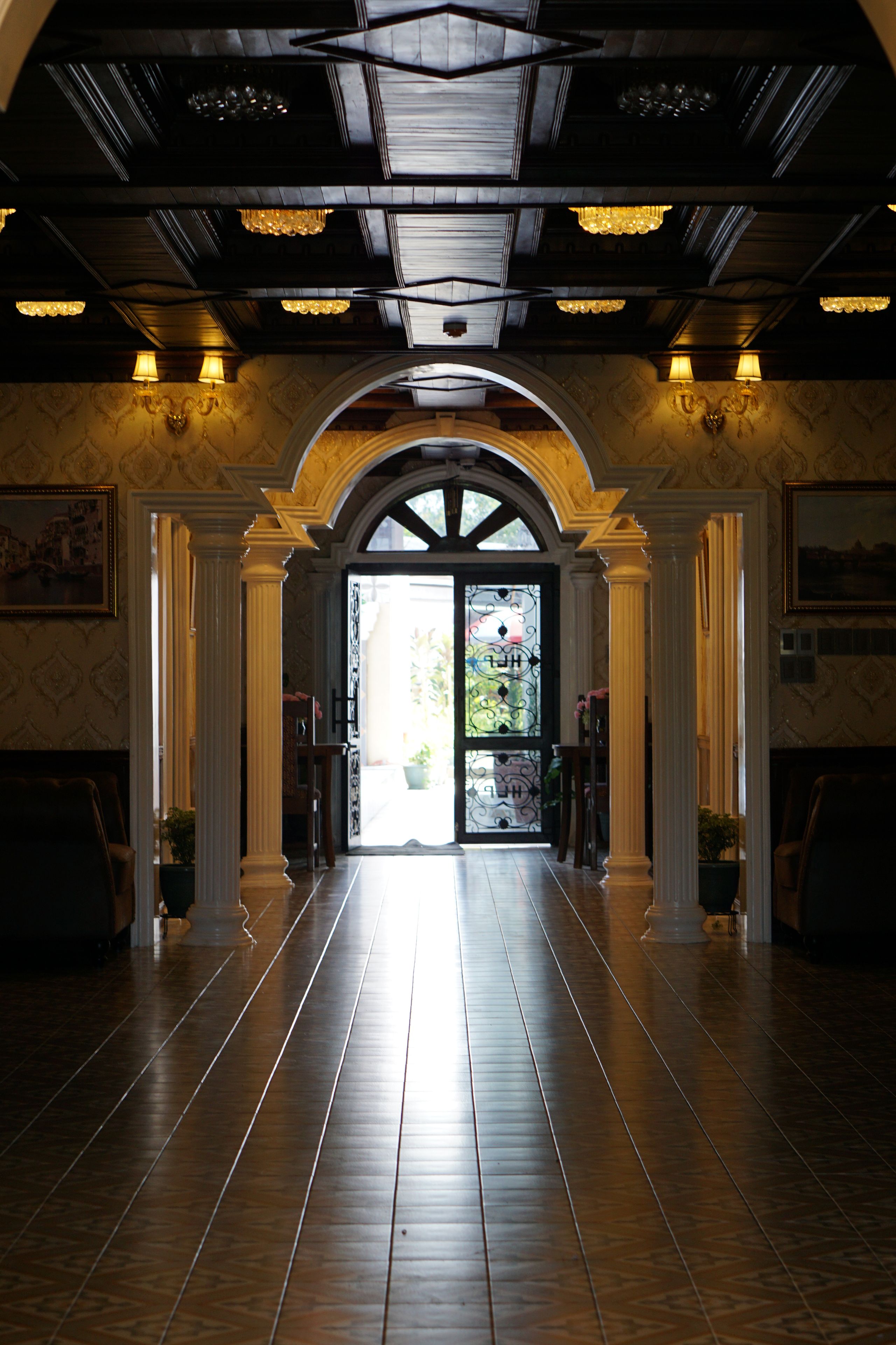 A grand hallway with a high ceiling, arched doorway, and a view of the outdoors.