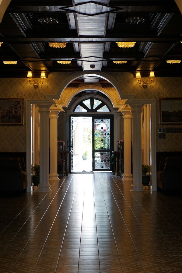 A grand hallway with a high ceiling, arched doorway, and a view of the outdoors.