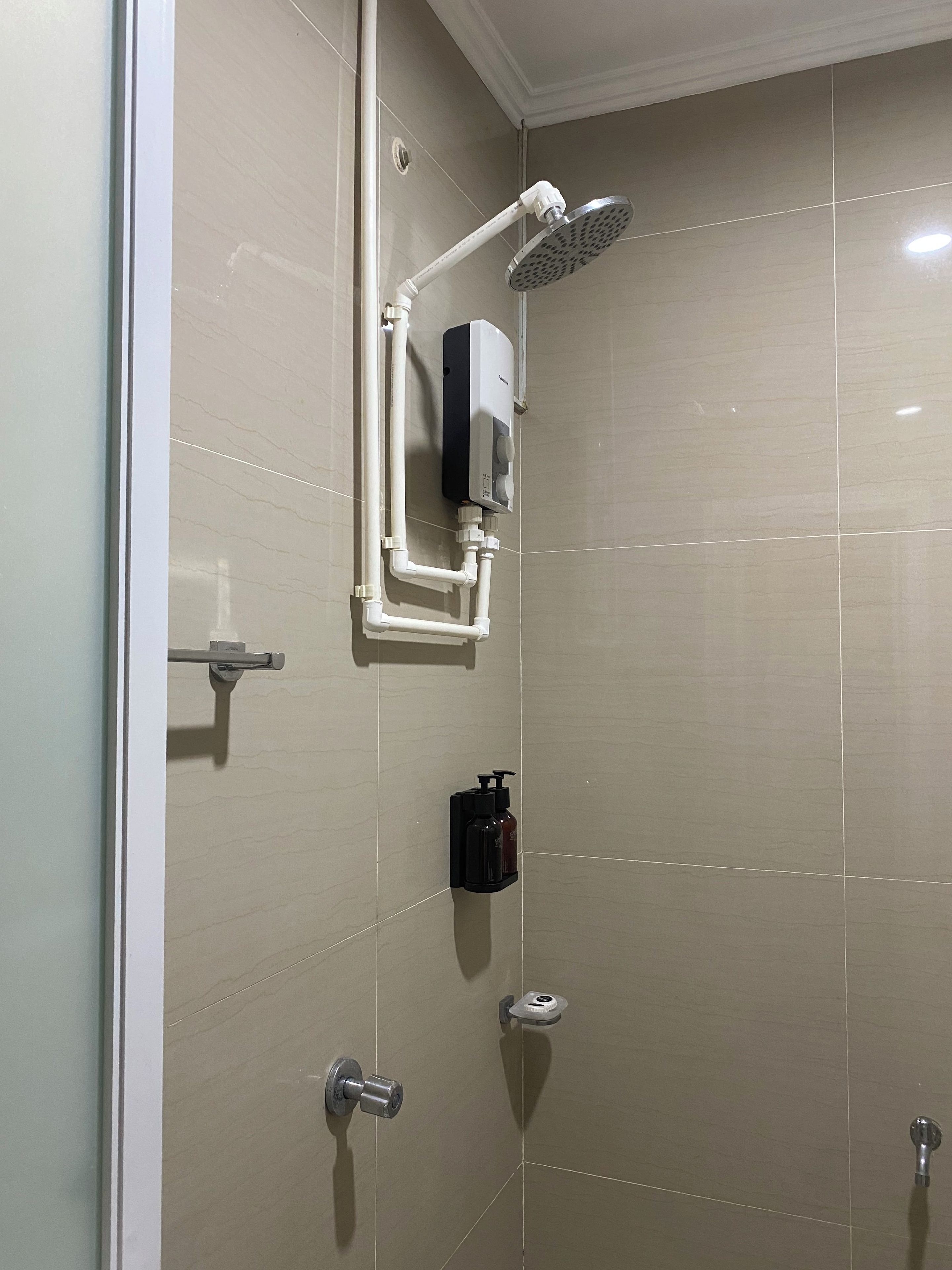 A bathroom with a shower, a hand dryer, and a soap dispenser.