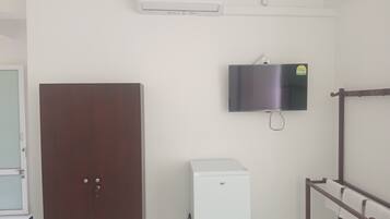 A room with a wardrobe, a small white appliance, a mounted television, and a towel rack.