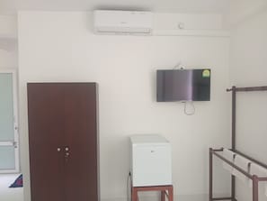 A room with a wardrobe, a small white appliance, a mounted television, and a towel rack. - Kingdom Gate Holiday Inn (Katugastota)