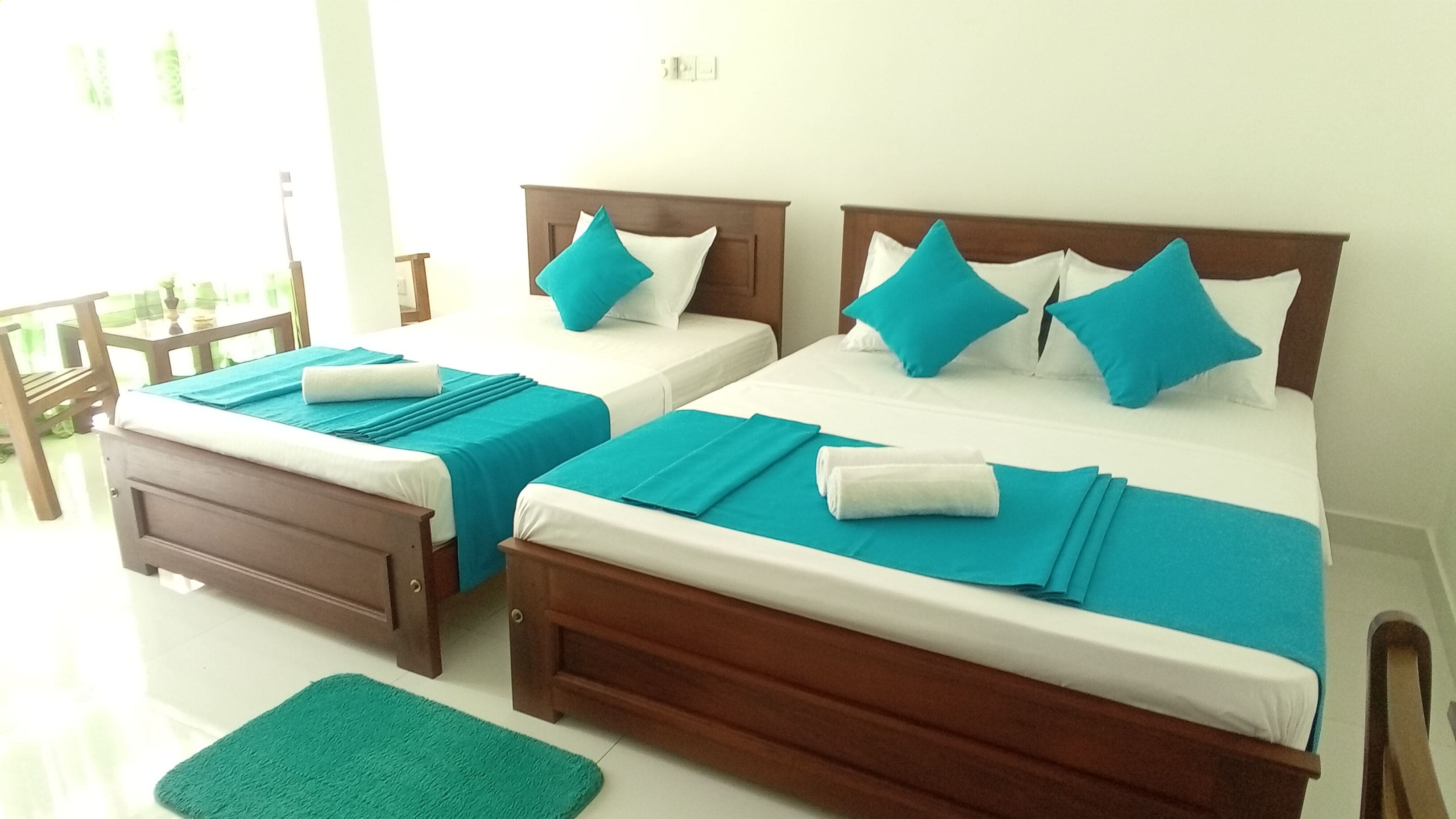 Two twin beds with matching headboards and footboards, each with a teal bedspread and white pillows.