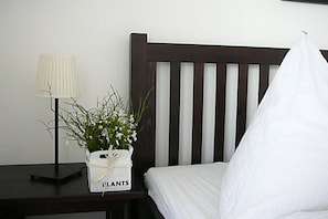 A bed with a white pillow and a nightstand with a lamp and a plant. - Holiday apartment with 1 bedroom (Konstanz)
